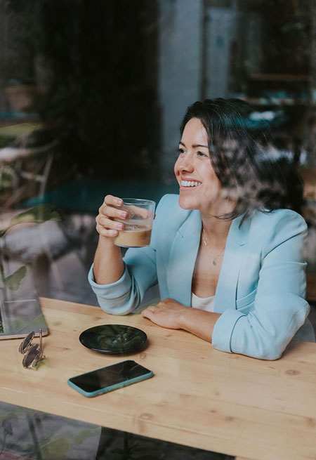 Frannie Coggeshall sits at a window drinking iced coffee