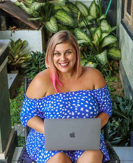 Esther Inman smiling at the camera holding a laptop