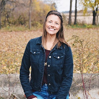 Kerri, Right Hand Woman at Elevate Her Marketing, smiles at the camera wearing a jean jacket